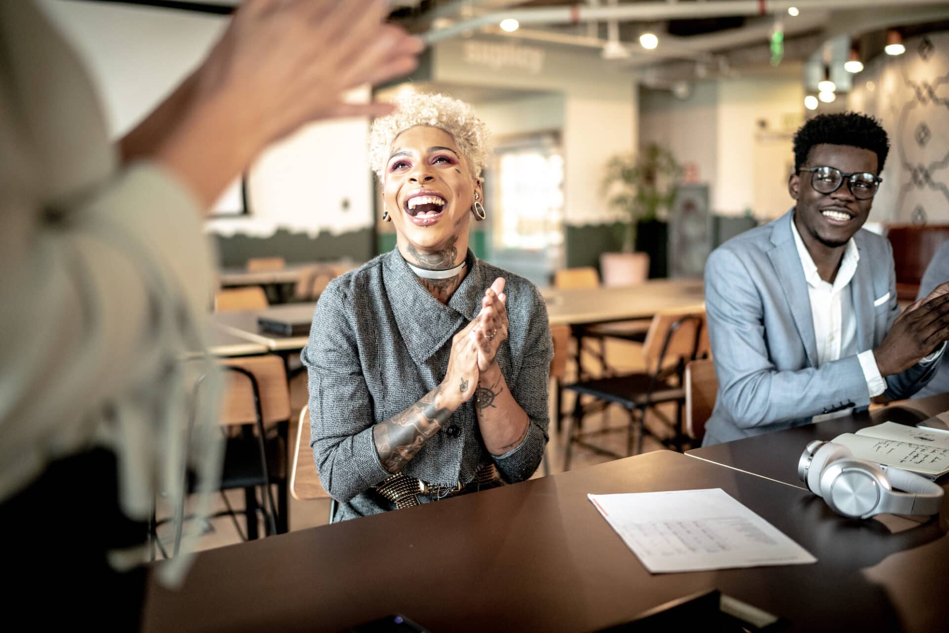 Happy business people in a team meeting, cheering and clapping.