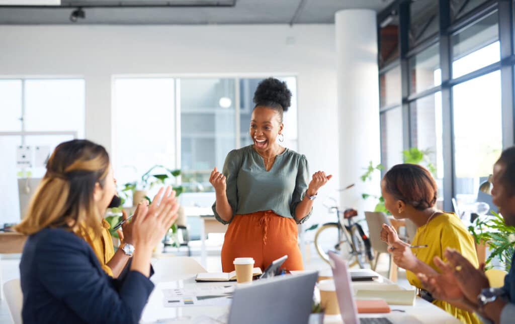 Happy employees in an office are celebrating their new corporate language training.