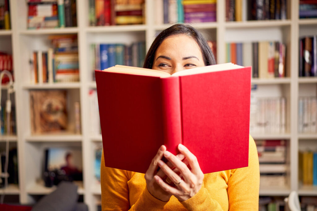 Lächelnde Frau hält ein Buch hoch, mit dem sie Sprachen lernt.
