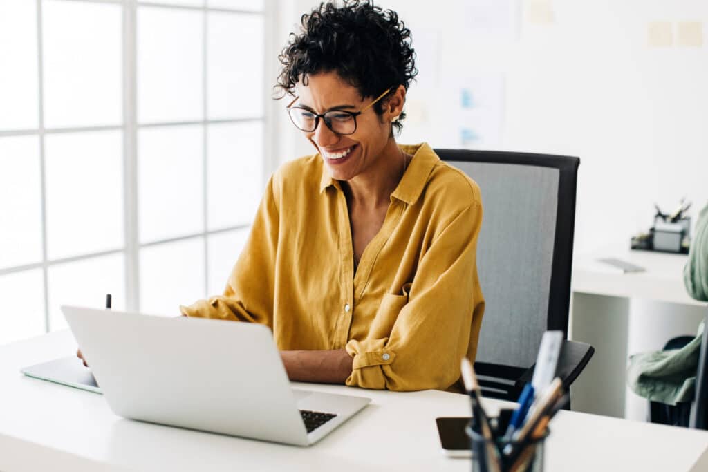 A smiling busines woman is taking one-on-one video language learning sessions with Babbel Intensive on her laptop.