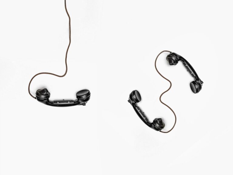 Foto mit drei schwarzen Telefonhörern, wobei zwei davon miteinander verbunden sind; als Symbol für die Bedeutung guter Teamkommunikation.