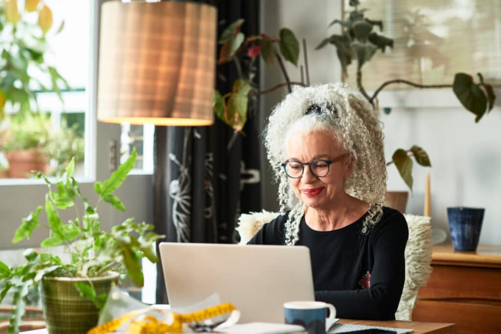 A smiling business woman is finding her individual language learning level on her laptop at home.