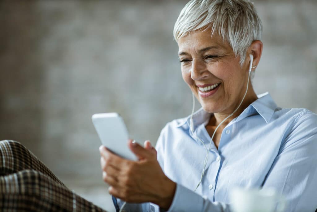 Lächelnde Frau lernt Business Englisch auf ihrem Smartphone.