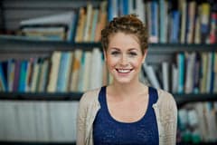 Smiling office worker standing in front of a book shelf.