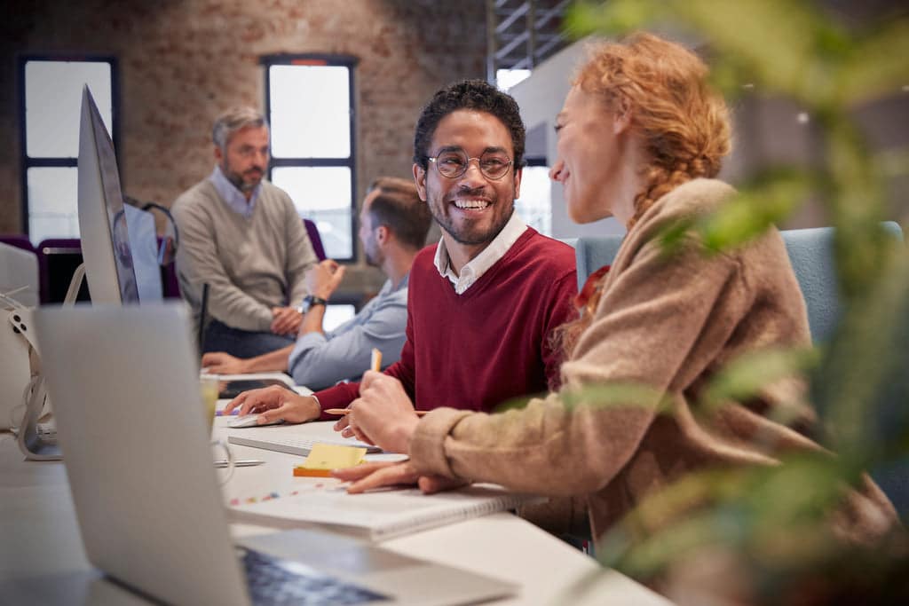 2 smiling coworkers are talking to each other.