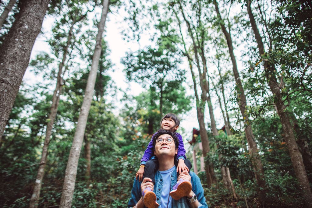 Smiling father and daughter are walking in a forest.