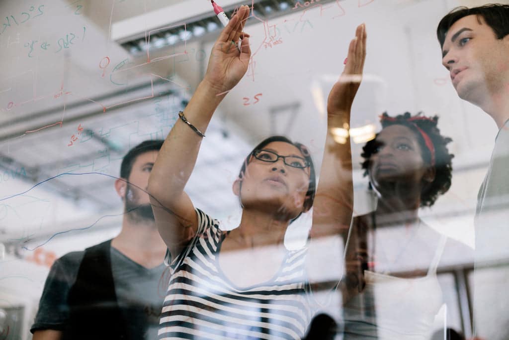 Business people writing their goals on a glass board.