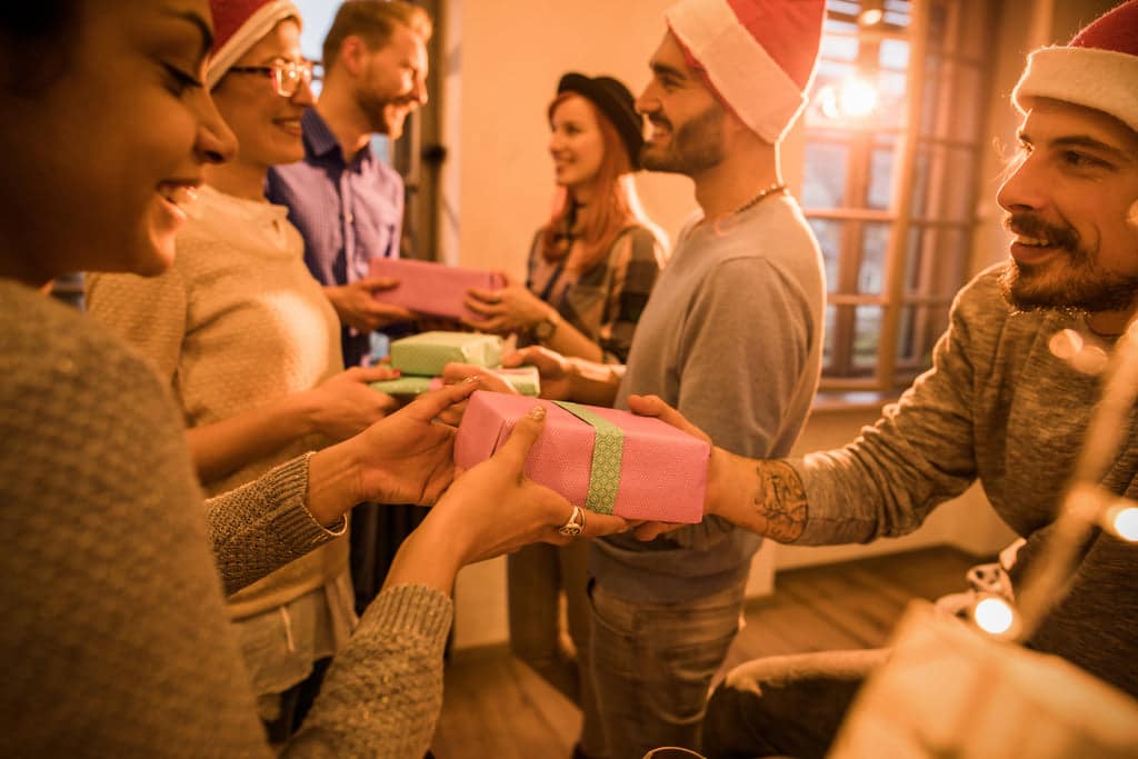 Smiling employees are exchanging Christmas gifts.