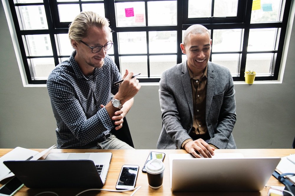 Two colleagues working together on their laptops