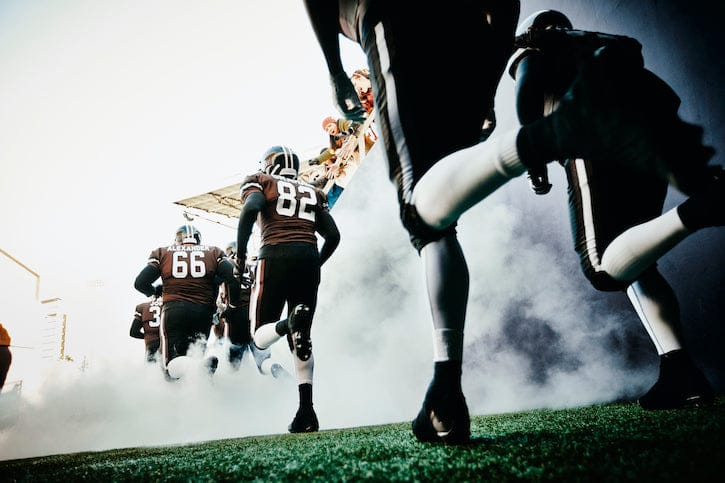 An American Football sports team is running on the field.