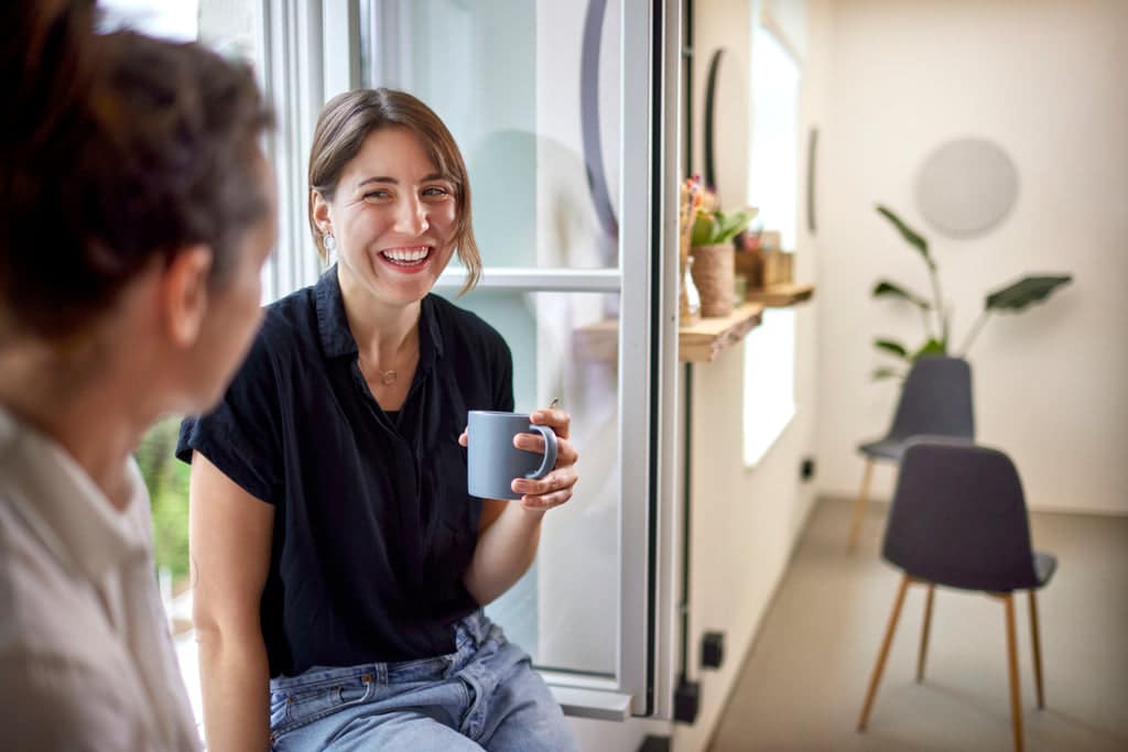 Smiling business woman talks to her co-worker.