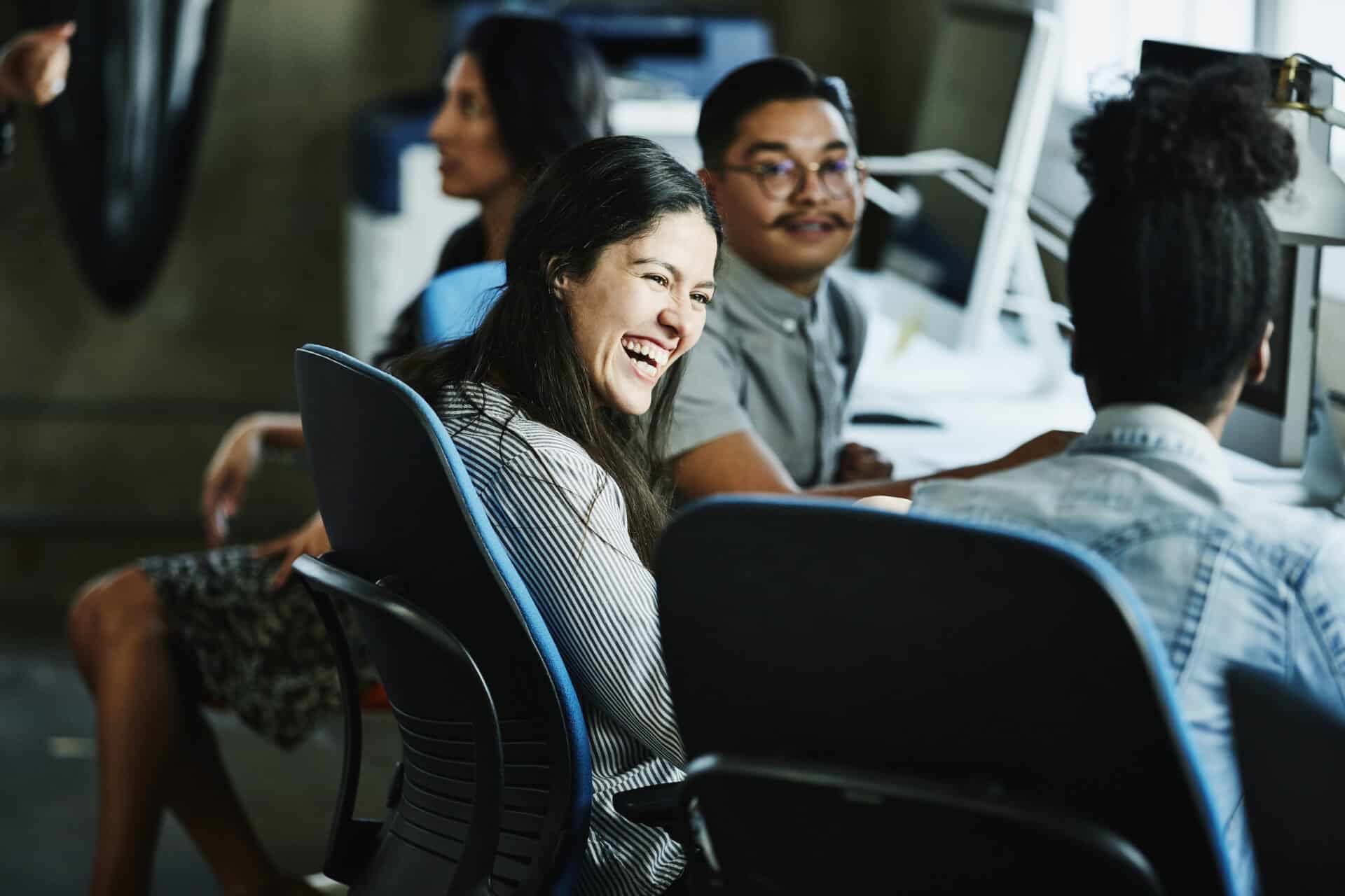 Group of coworkers talking and laughing together at their workplaces.