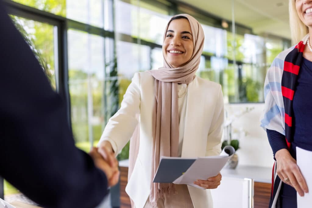 Smiling employee is shaking hands with her team leader.