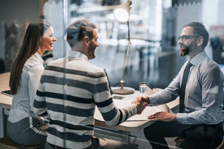 A banker is shaking hands with a couple after giving counceling.