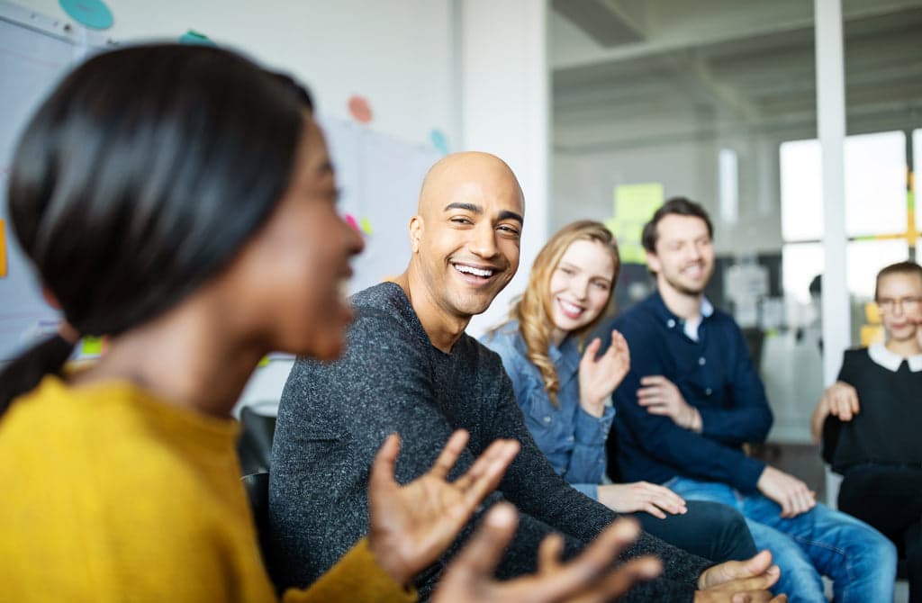 Lächelnde Büroangestellte reden in einem Meeting miteinander.