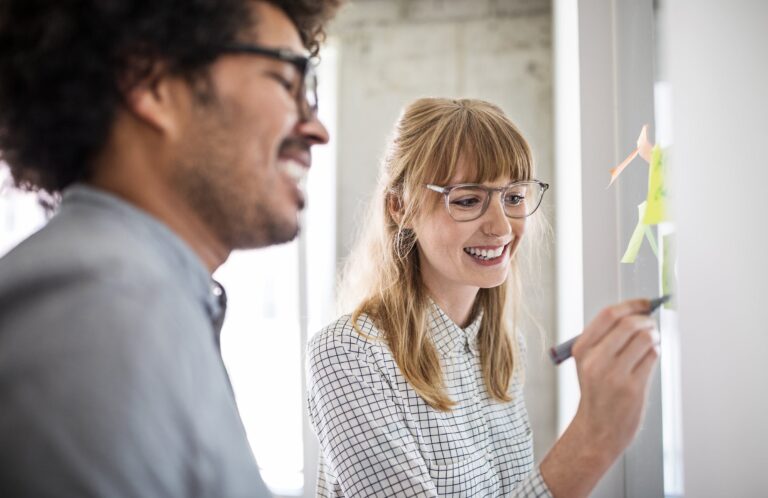 Mitarbeiter:innen arbeiten an einem Projekt an einem Whiteboard.