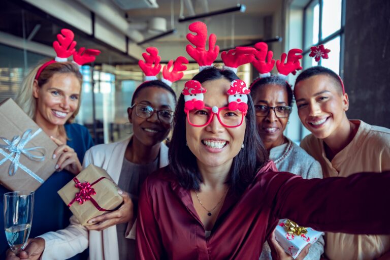 Mitarbeiter:innen feiern Weihnachten im Büro und tauschen Geschenke aus.