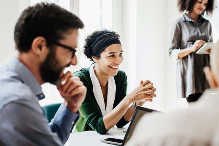 Lächelnde Büroangestellte reden in einem Meeting.