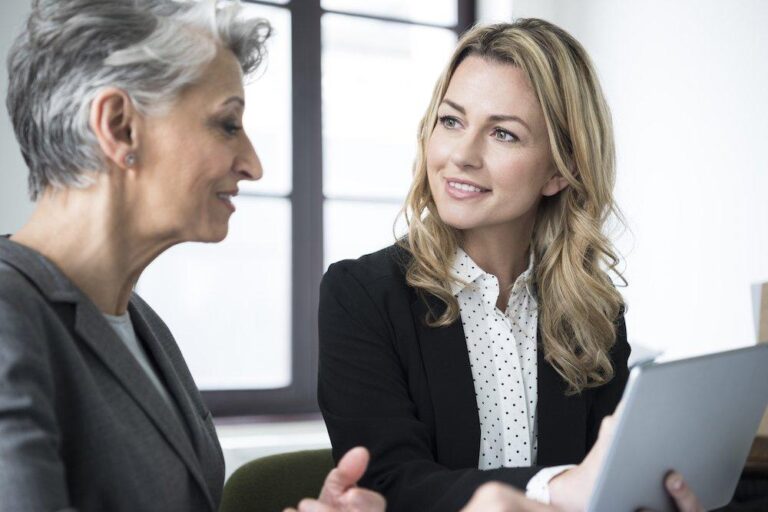 Zwei unterschiedlich alte Geschäftsfrauen sind in einem Mentoring-Gespräch vertieft.