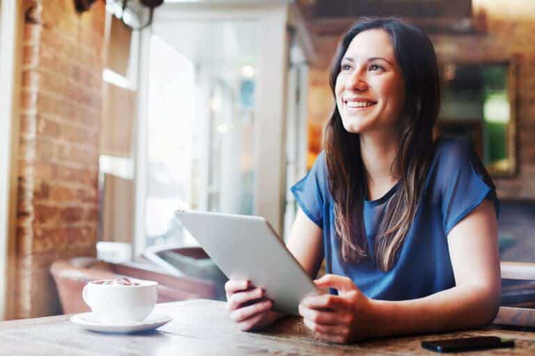 Lächelnde Frau mikrolernt auf ihrem Tablet in einem Café.