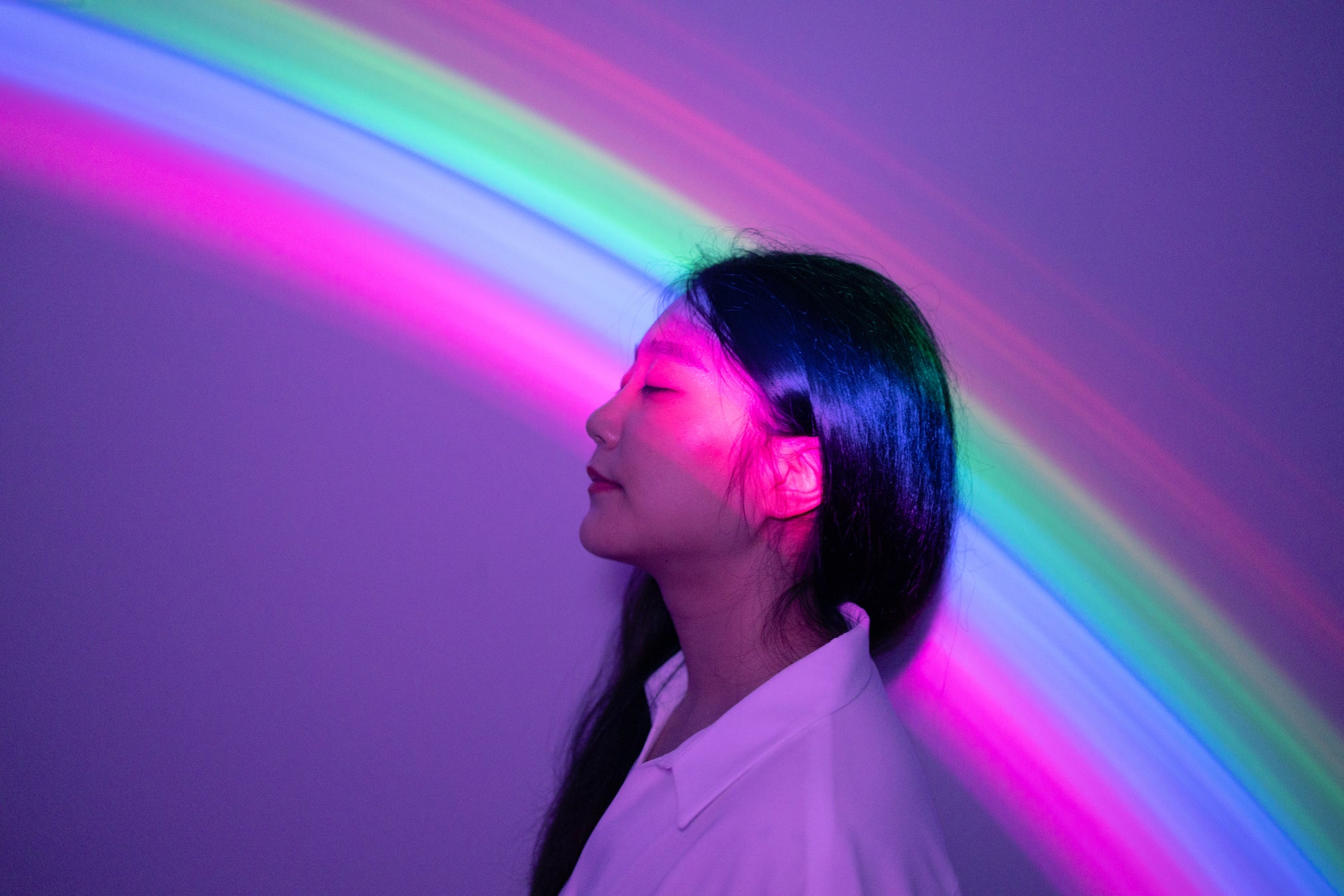 Regenbogenlichter scheinen über den Kopf einer jungen Frau als Symbol für Inspiration.