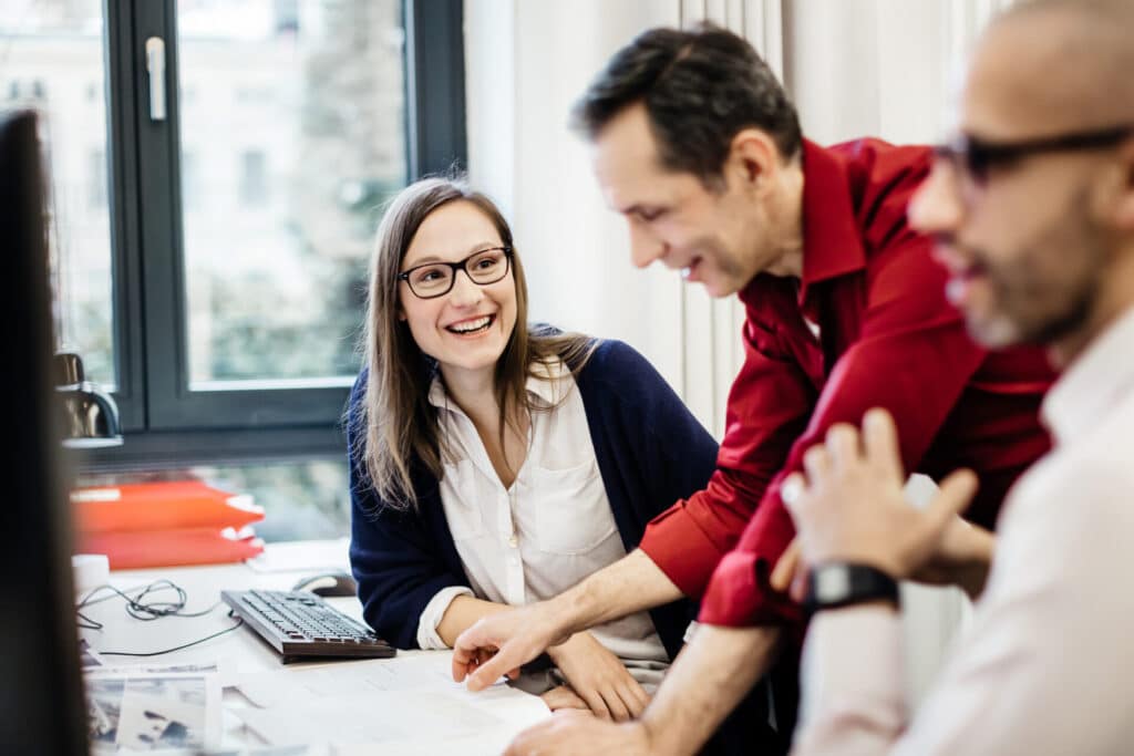 Smiling colleagues are chatting at the workplace in an office.