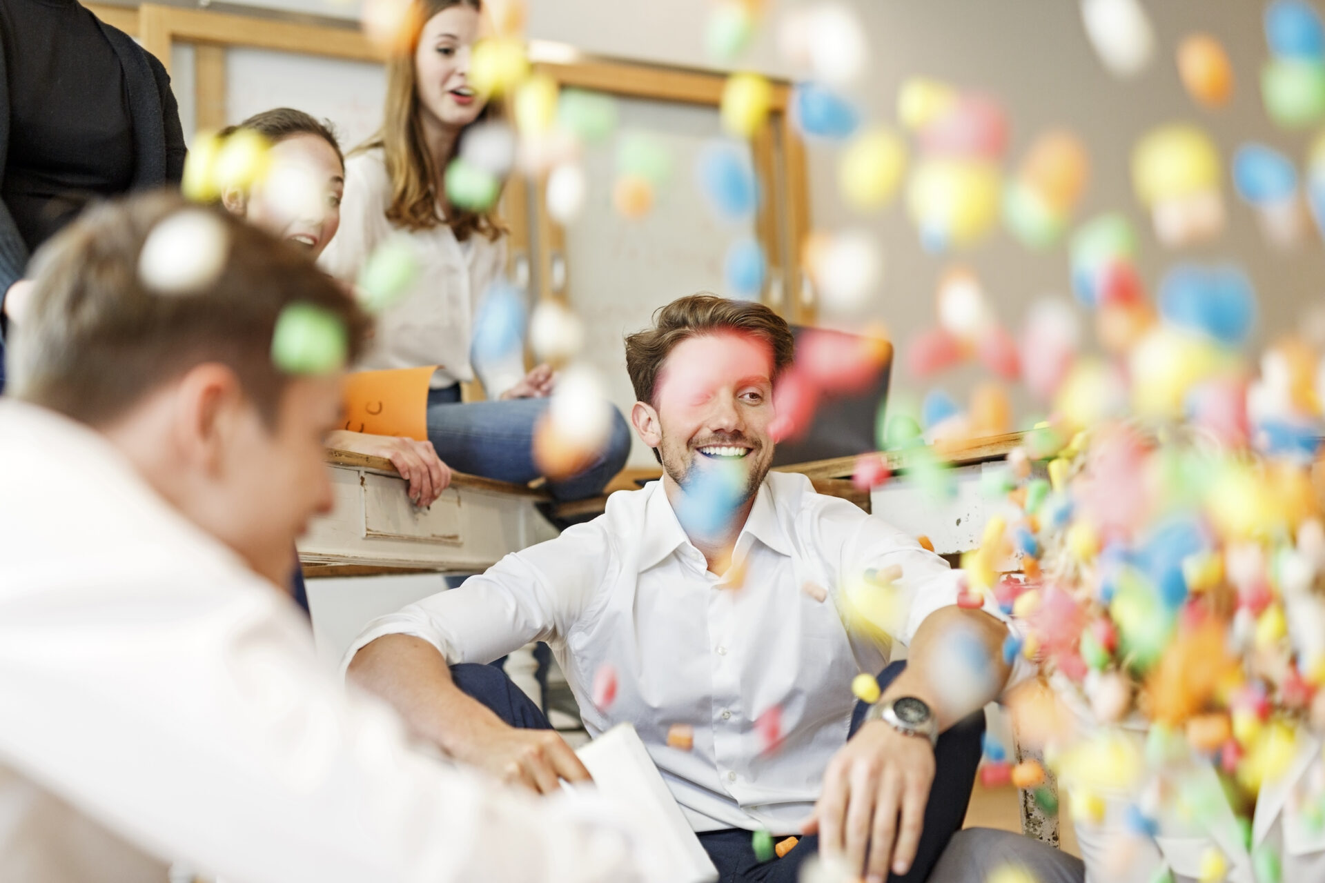 Happy employees are throwing confetti in the office, after winning a gamified challenge.