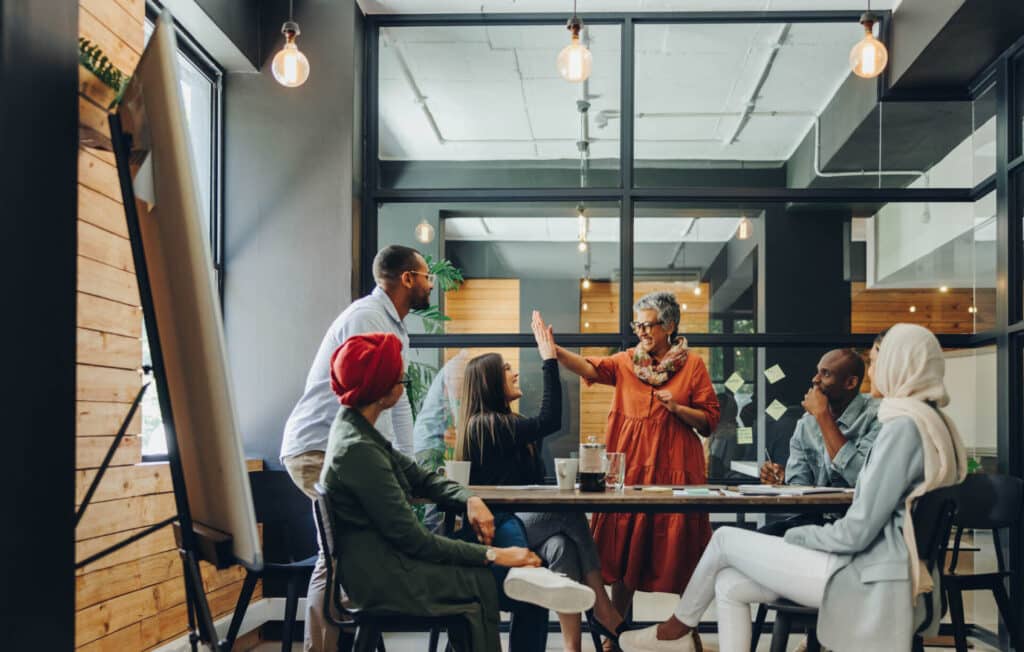 Business people giving each other a high five, after winning a gamified challenge at work.