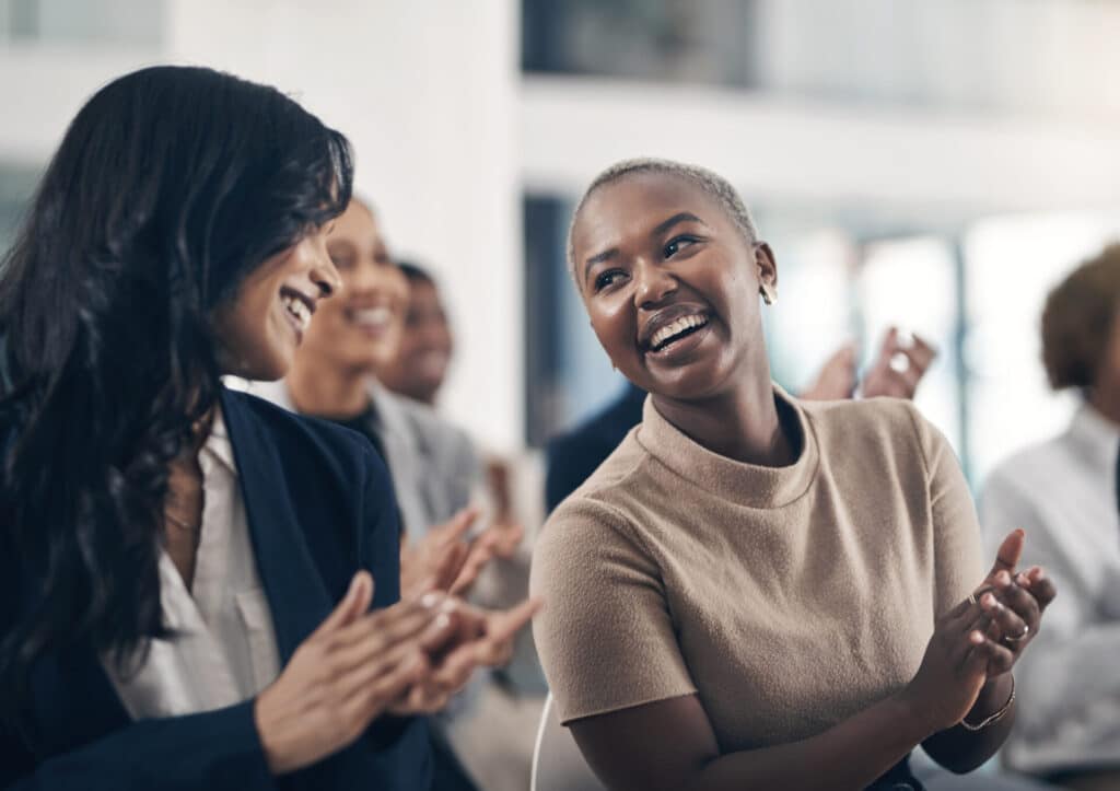 Smiling employees are clapping because they are having a great employee experience.