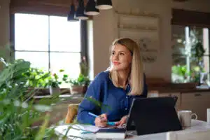 Lächelnde Frau lernt am Computer bei der Arbeit im Homeoffice eine Sprache.