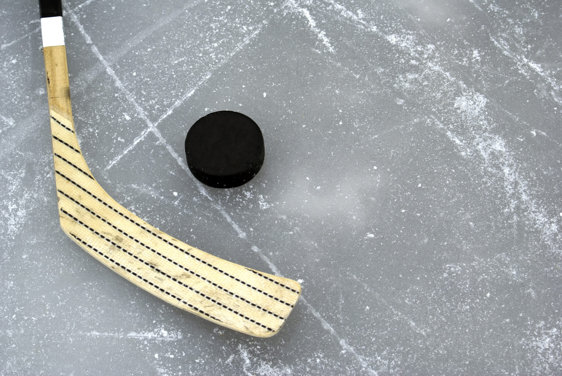 Hockey stick and black puck on ice