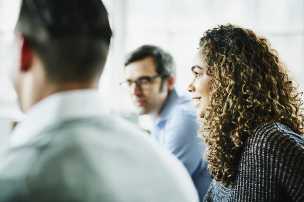 Smiling businesswoman in discussion with colleagues during a team meeting.