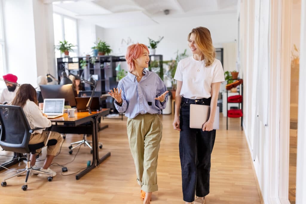 Zwei Arbeitskolleginnen unterhalten sich im Büro über ihren Urlaub.