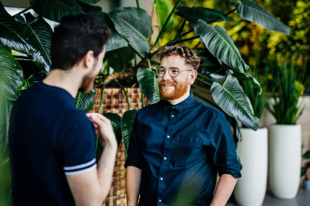 Two young business men are talking about their vacation in the office.