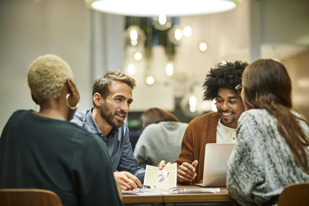 Junge, lächelnde Geschäftsleute unterhalten sich in einem Café.