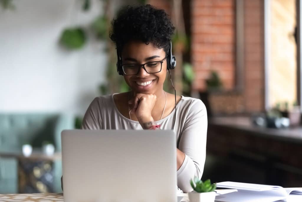 Smiling young woman is learning a language on her laptop.