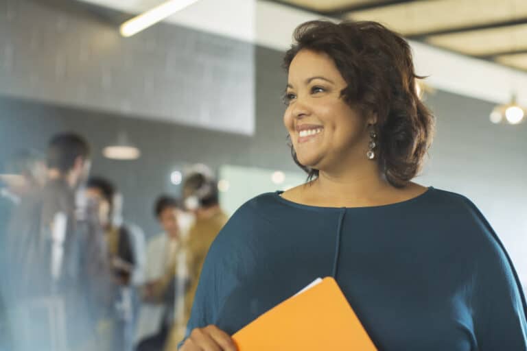 Smiling business woman is standing in an office.