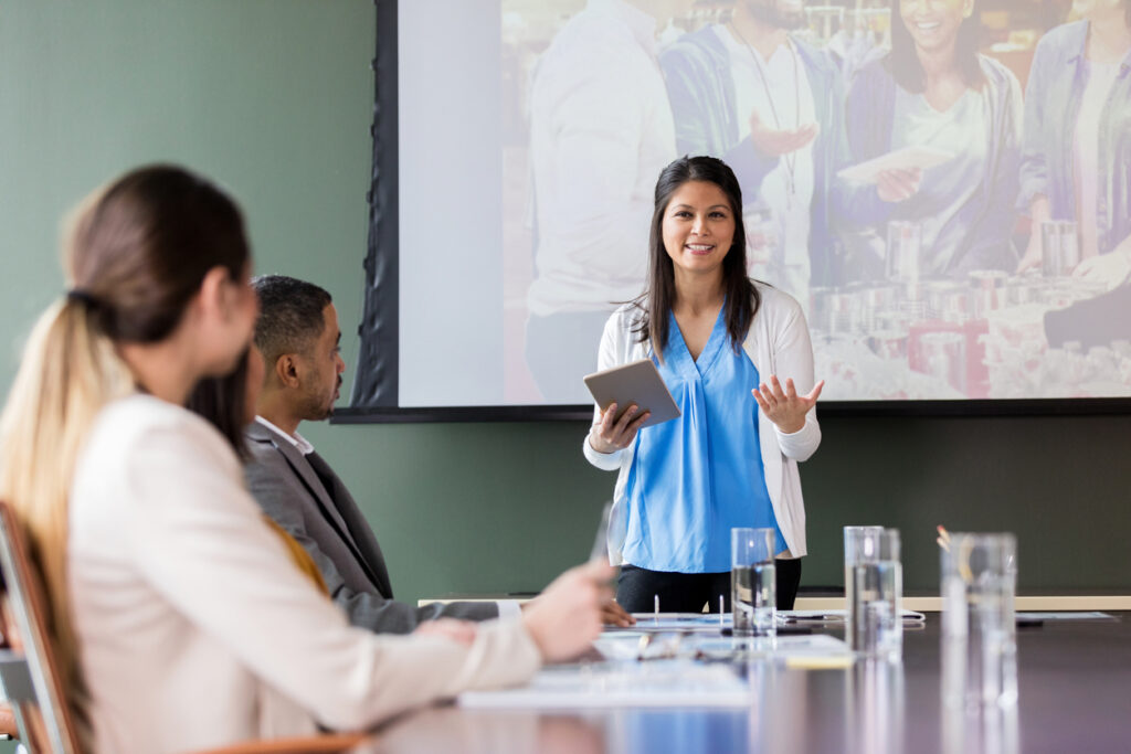Young business woman holding a presentation in an office, as a symbol of strong self-efficacy.