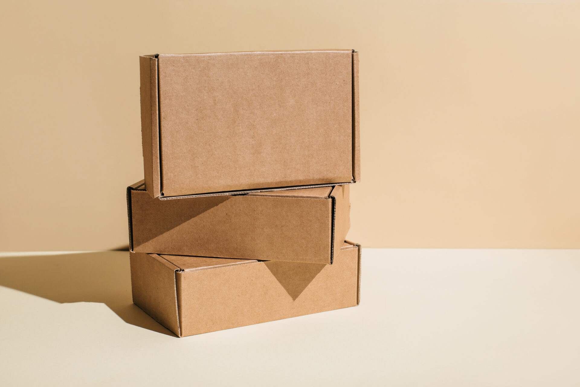 Brown cardboard boxes stacked on top of each other on a beige background, copy space