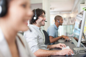 Lächelnde Mitarbeitende machen eine digitale Mitarbeiterschulung und arbeiten an ihren Computern.