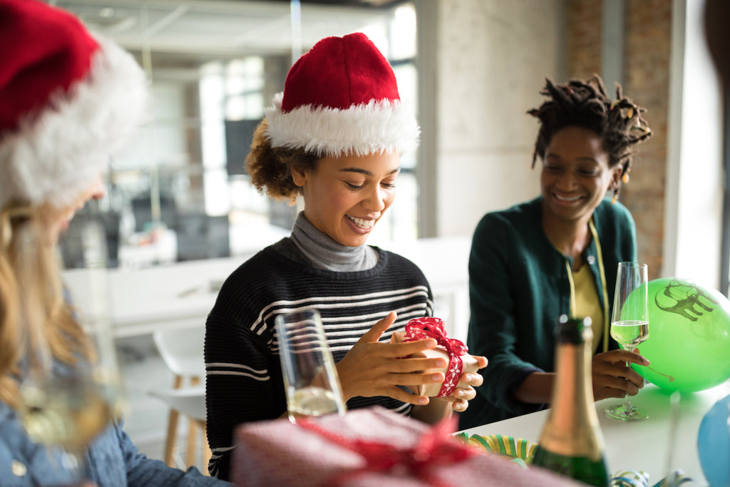 Happy employees open gifts at an office christmas party.