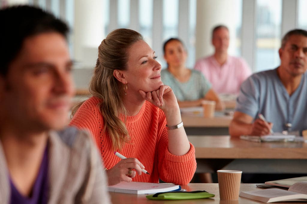 Lächelnde Mitarbeiter:innen, die in einem Kurs lernen.