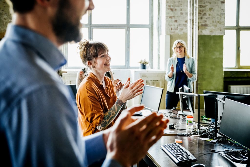 Fröhliche Mitarbeiter:innen unterhalten sich im Büro.